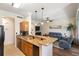 Stylish kitchen with granite countertops, breakfast bar, wood cabinets, and an open view into the living room at 600 Gardens Edge Dr # 613, Venice, FL 34285