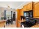 Bright kitchen area featuring granite countertops, wood cabinetry, black appliances, and adjacent dining space at 600 Gardens Edge Dr # 613, Venice, FL 34285