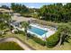 Aerial view of a community pool area with lounge chairs, manicured landscaping, and a nearby clubhouse for residents at 600 Gardens Edge Dr # 613, Venice, FL 34285