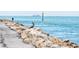 Waterfront view featuring a pelican on the rocks and a fisherman in the background at 600 Gardens Edge Dr # 613, Venice, FL 34285