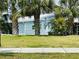 Charming blue home surrounded by lush landscaping and green grass at 615 S Green Cir, Venice, FL 34285