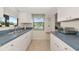 White kitchen with stainless steel sink, ample cabinetry, and an eat-in stool at 6796 Gasparilla Pines Blvd # 18, Englewood, FL 34224