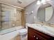 Updated bathroom features a tub with tiled shower, cherry cabinet vanity with marble countertop, and round mirror at 701 Barcelona Ave # 101, Venice, FL 34285