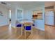 Open-concept dining room with a round table and blue chairs, adjacent to kitchen with white cabinets and appliances at 701 Barcelona Ave # 101, Venice, FL 34285