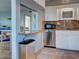 Kitchen bar area and view of stainless steel dishwasher and sink with white cabinets at 701 Barcelona Ave # 101, Venice, FL 34285