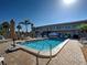 Sparkling community pool surrounded by lounge chairs, shady umbrellas, picnic tables and lush landscaping at 701 Barcelona Ave # 101, Venice, FL 34285
