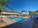 Exterior view of complex with pool, lounge chairs, shady umbrellas, lush landscaping and nearby parking at 701 Barcelona Ave # 101, Venice, FL 34285