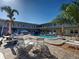Community pool features lounge chairs, picnic tables, shady umbrellas and palm trees on a sunny day at 701 Barcelona Ave # 101, Venice, FL 34285