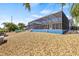 Back of house with a screened in pool and patio surrounded by lush, tropical landscaping and rock at 731 Flamingo Dr, Apollo Beach, FL 33572