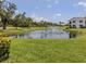 Scenic view of a lush community pond with a fountain, surrounded by well-maintained green spaces and trees at 800 Capri Isles Blvd # 124, Venice, FL 34292
