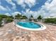 Community pool featuring clear blue water, surrounded by a paved deck, landscaping, and privacy fencing at 832 Whitecap Cir # 5, Venice, FL 34285