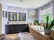 Elegant bathroom featuring double vanity, soaking tub, decorative artwork, and a plush rug for added comfort at 9019 39Th Street Cir E, Parrish, FL 34219