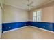 This bedroom features neutral paint, a ceiling fan, shutters, tiled floors and blue lower wall trim at 912 Barclay Ct, Venice, FL 34293