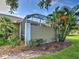 View of a home's screened-in patio surrounded by lush greenery, with a well-manicured lawn at 912 Barclay Ct, Venice, FL 34293