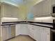 Bright kitchen with white cabinetry, black counters, and a stainless steel dishwasher at 912 Barclay Ct, Venice, FL 34293