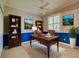 Home office with dark wood desk, rug, ceiling fan, built-in bookshelves and blue lower wall trim at 912 Barclay Ct, Venice, FL 34293