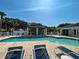 Inviting community pool area featuring lounge chairs and shaded seating under a clear, sunny sky at 912 Barclay Ct, Venice, FL 34293