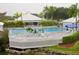 Community pool with ample seating surrounded by well-maintained landscaping and a view of the clubhouse at 912 Barclay Ct, Venice, FL 34293