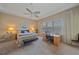 Calm bedroom featuring a tray ceiling, plantation shutters, and an adjacent office desk at 9220 43Rd W Ter, Bradenton, FL 34209