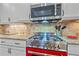Close up of kitchen range with a red oven, granite countertops, modern appliances, and tiled backsplash at 9220 43Rd W Ter, Bradenton, FL 34209
