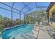 Private screened-in pool with waterfall feature, lush landscaping, and comfortable lounge chairs at 9220 43Rd W Ter, Bradenton, FL 34209