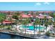 Stunning aerial view of the community pool and clubhouse with palm trees and ocean views beyond the red tile roofs at 97 Vivante Blvd # 306, Punta Gorda, FL 33950