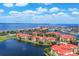 An aerial view shows an island neighborhood with red roofs surrounded by canals and a body of water beyond at 97 Vivante Blvd # 306, Punta Gorda, FL 33950