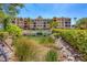 Exterior view of building featuring lush landscaping, parking area, and tranquil pond at 97 Vivante Blvd # 306, Punta Gorda, FL 33950