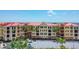 Exterior view of building featuring lush landscaping, colorful facades, and well maintained parking area at 97 Vivante Blvd # 306, Punta Gorda, FL 33950