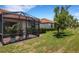 Landscaped backyard features a covered patio, lush green grass, and mature trees at 9823 Haze Dr, Venice, FL 34292