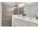 Modern bathroom with double sinks, white cabinets, and tiled shower with glass doors at 9823 Haze Dr, Venice, FL 34292