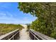 Scenic beach access with a wooden walkway framed by lush greenery, leading to the sandy shores at 9823 Haze Dr, Venice, FL 34292