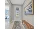 Inviting entryway with white tile floors, decorative glass door, bench, and art at 10121 Beachwalk Dr, Englewood, FL 34223