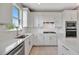 Modern kitchen features white cabinetry, stainless steel appliances, and bright natural lighting at 10121 Beachwalk Dr, Englewood, FL 34223
