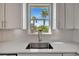 Bright kitchen featuring a stainless steel sink, white cabinets, and a picturesque window view of palm trees at 10121 Beachwalk Dr, Englewood, FL 34223