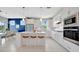 Bright kitchen boasts white cabinetry, stainless steel appliances, and a large island with bar seating at 10121 Beachwalk Dr, Englewood, FL 34223