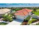 Aerial view of a charming home featuring lush landscaping, red roof, and attached garage at 102 Mestre Pl, North Venice, FL 34275