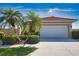 Inviting home featuring lush landscaping, mature palm trees, and an attached two-car garage at 102 Mestre Pl, North Venice, FL 34275