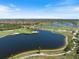 Panoramic aerial view of a golf course featuring a scenic lake and meticulously manicured green fairways at 10209 Fiddlewood Dr, Venice, FL 34293