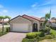 Charming single-story home featuring a red tile roof, lush landscaping, and a brick driveway at 10209 Fiddlewood Dr, Venice, FL 34293