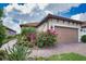 A detailed exterior image showing the brick paved walkway and two car garage with beautiful landscaping at 10410 Inglenook Ter, Palmetto, FL 34221