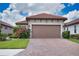 Home featuring a two-car garage, brick paved driveway and exterior landscaping with bougainvillea at 10410 Inglenook Ter, Palmetto, FL 34221