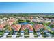 Aerial view of homes with tile roofs and lush landscaping surrounding a tranquil community pond at 10930 Lerwick Cir, Englewood, FL 34223