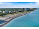 Expansive aerial shot showcasing a sandy beach, clear blue ocean, and nearby residential buildings at 10930 Lerwick Cir, Englewood, FL 34223