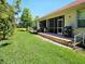 Inviting backyard with screened lanai, brick patio, grill, and lush lawn for outdoor enjoyment at 10930 Lerwick Cir, Englewood, FL 34223
