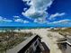 Stunning beach view with stairs to access the sand, blue skies, and fluffy clouds at 10930 Lerwick Cir, Englewood, FL 34223