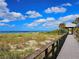 Scenic beach with a wooden boardwalk, native plants, and a clear view of the ocean at 10930 Lerwick Cir, Englewood, FL 34223