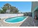 Relaxing pool area with screened lanai and a white privacy fence surrounded by palms at 1099 Nokomis S Ave, Venice, FL 34285