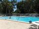Community pool with bright blue water and a pool fence; lush tropical landscape in the background at 1154 Bird Bay Way # 303, Venice, FL 34285