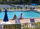 Relaxing pool area featuring lounge chairs, shady umbrellas, and a view of the tennis court at 1154 Bird Bay Way # 303, Venice, FL 34285
